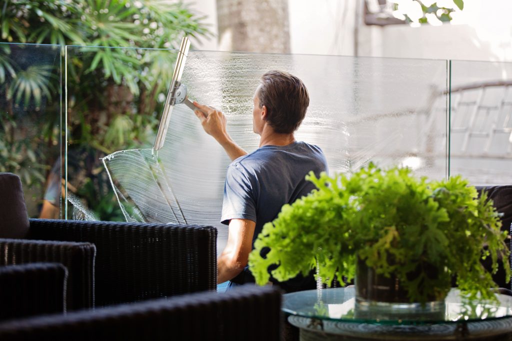 Man cleaning plexiglass around office space